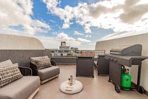 a patio with a grill and furniture on a roof at Scholtz Penthouse in Cape Town