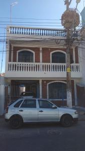 een witte auto geparkeerd voor een gebouw bij voltamos a funcionar casa da mãe Aparecida in Aparecida
