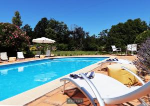 una piscina con sillas, una mesa y una sombrilla en MyStay - Casa de Abbades, en Gandra