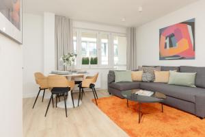 - un salon avec un canapé, une table et des chaises dans l'établissement Warsaw City Center Apartments by Renters, à Varsovie