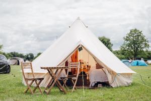 Remenham Farm during Henley Royal Regatta في Lower Assendon: خيمة بيضاء مع طاولة وكراسي في ميدان