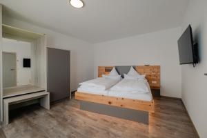 um quarto com uma cama com lençóis brancos e uma televisão em Südseequartier em Elsterheide