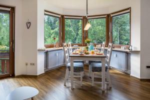 - une salle à manger avec une table, des chaises et des fenêtres dans l'établissement Friedolin, à Titisee-Neustadt