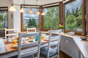 - une salle à manger avec une table, des chaises et des fenêtres dans l'établissement Friedolin, à Titisee-Neustadt