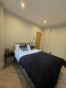 a bedroom with a large bed with black blankets and pillows at Luxury 2 bed 1 bath in Central London by Graceful Apartments in London