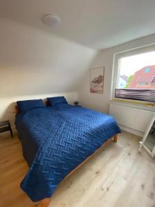 Un dormitorio con una cama azul y una ventana en Haus Sunshine - Ferienwohnung Sunshine 1, en Hessisch Oldendorf