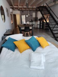 La Borie - Loft élégant et spacieux - WIFI في Puygouzon-et-Montsalvy: سرير أبيض مع أربعة وسائد ملونة عليه