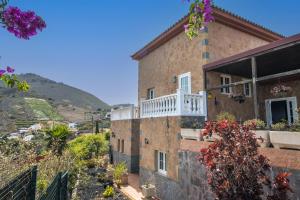 a brick house with a balcony and flowers at Villa Mirador Los Hoyos in Las Palmas de Gran Canaria