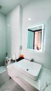 a white bathroom with a sink and a mirror at Xan hotel Phu Quoc in Phú Quốc