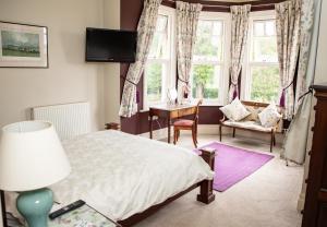 a bedroom with a bed and a desk and windows at Mere Brook House in Wirral