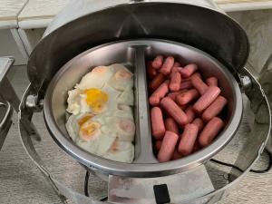 a pot of food with eggs and sausages at Reikartz Amirun Tashkent in Tashkent