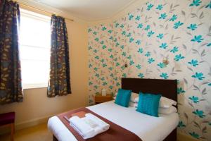 a bedroom with a bed with blue and white wallpaper at Royal Mackintosh Hotel in Dunbar