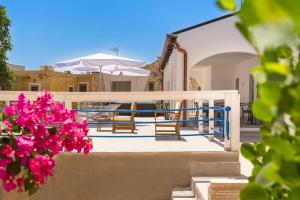 uma varanda com cadeiras e um guarda-sol e flores em DipintodiBlu Charming House em Lampedusa
