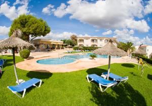 een zwembad met 2 ligstoelen en parasols bij Apartamentos Sol Romántica by DOT Suites in Cala Romantica