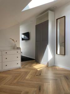 ein weißes Zimmer mit einer Kommode und einem Spiegel in der Unterkunft Izabelės apartamentai. Butas - studija in Palanga