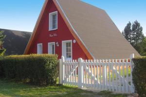 ein rotes Haus mit einem weißen Zaun davor in der Unterkunft Ferienhaus Chrissi in Quilitz