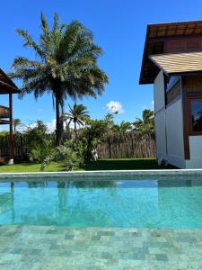 a swimming pool in front of a house with a palm tree at Pequena Lua Flats - Península de Maraú in Barra Grande