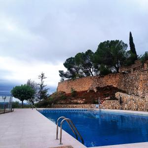 a swimming pool in front of a stone wall at Hotel Balcó del Priorat in La Morera de Montsant