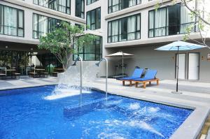 a swimming pool with a fountain in front of a building at Beston Pattaya - SHA Plus Certified in Pattaya South