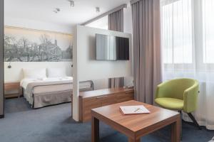 ヴロツワフにあるTerminal Hotelのベッド、テーブル、椅子が備わるホテルルームです。