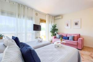 sala de estar con 2 camas y sofá rosa en OleHolidays 1106 Romana Playa primera línea playa, en Marbella