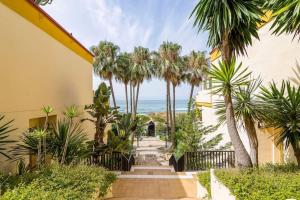 un pasillo del complejo con palmeras y el océano en OleHolidays 1106 Romana Playa primera línea playa, en Marbella