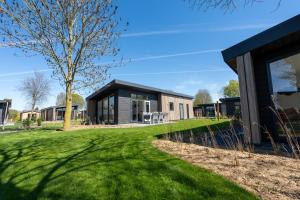 een huis met een zwart dak op een groene tuin bij De Lithse Ham in Lith