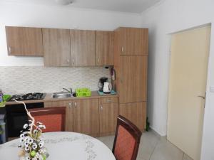 a kitchen with wooden cabinets and a white table with a tableablish at Apartman David in Barbat na Rabu