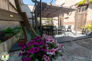 a patio with a table and some purple flowers at LA GOUTTE D'OR in Avize