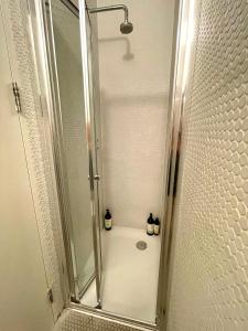 een douche met een glazen deur met 2 flessen bij Cosy Shoreditch flat in Londen