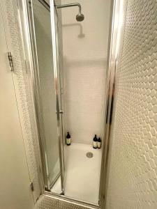 ducha con puerta de cristal y 2 botellas en Cosy Shoreditch flat, en Londres