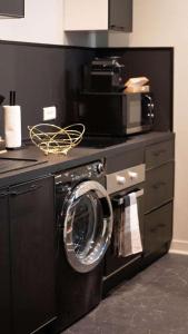 a washing machine in a kitchen with a microwave at Escapade Urbaine - Balnéothérapie - Cinéma au Cœur de la Ville in Mâcon