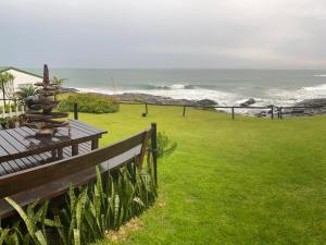 a bench in a field with the ocean in the background at Mazeppa Sunrise Beach Accommodation in Mazeppa Bay