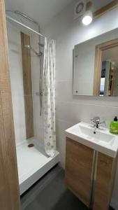 a bathroom with a shower and a sink and a tub at Apartament U Waldka in Mechelinki
