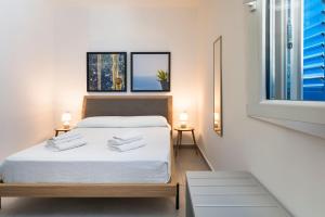 um quarto com uma cama com lençóis brancos e uma janela em DipintodiBlu Charming House em Lampedusa