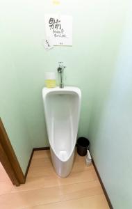 um urinol numa casa de banho com uma parede verde em おせっかいゲストハウス 昭和の寅や em Chikuma
