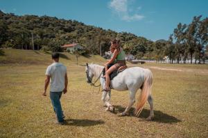 a woman riding a white horse next to a man at Hotel Termas da Guarda in Tubarão
