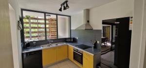 a kitchen with yellow cabinets and a stove top oven at L'Appart'Canon in Bout de lʼÉtang