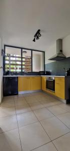 a large kitchen with yellow cabinets and a stove at L'Appart'Canon in Bout de lʼÉtang