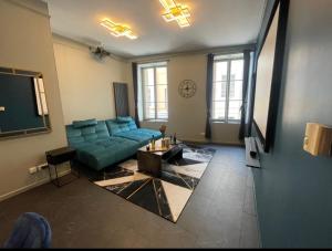 a living room with a green couch and a table at Escapade Urbaine - Balnéothérapie - Cinéma au Cœur de la Ville in Mâcon