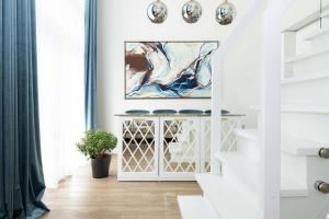 a white staircase in a living room with art on the wall at Season Surprise Apartment, By Cohost in Palanga