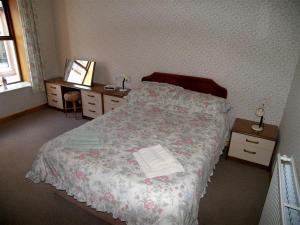 a bedroom with a bed and two tables and a window at Ernambrie Cottage in Castle Douglas