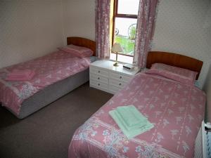 a bedroom with two beds and a window at Ernambrie Cottage in Castle Douglas
