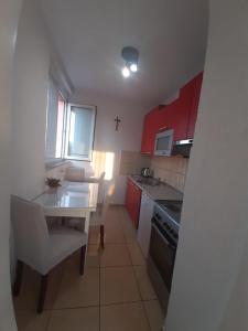 - une petite cuisine avec des placards rouges et une table blanche dans l'établissement Apartman Vukoja - Posušje, à Posušje