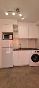 una cucina con armadi bianchi, lavandino e lavastoviglie di Estudio Elizondo 2 a Benidorm
