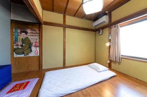 Postel nebo postele na pokoji v ubytování おせっかいゲストハウス 昭和の寅や