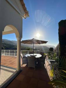 eine Terrasse mit einem Tisch und einem Sonnenschirm in der Unterkunft Casa Del Mar in Ponta do Sol