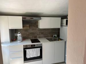 een kleine keuken met witte kasten en een wastafel bij Un Studio dans un endroit tranquille in Roquefort-les-Pins