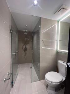 een badkamer met een toilet en een glazen douche bij Uptown Parksuites BGC in Manilla