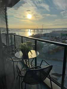 balcón con mesa, sillas y vistas a la puesta de sol en Apartamento nuevo, centrico y con vista a la bahia en Montevideo